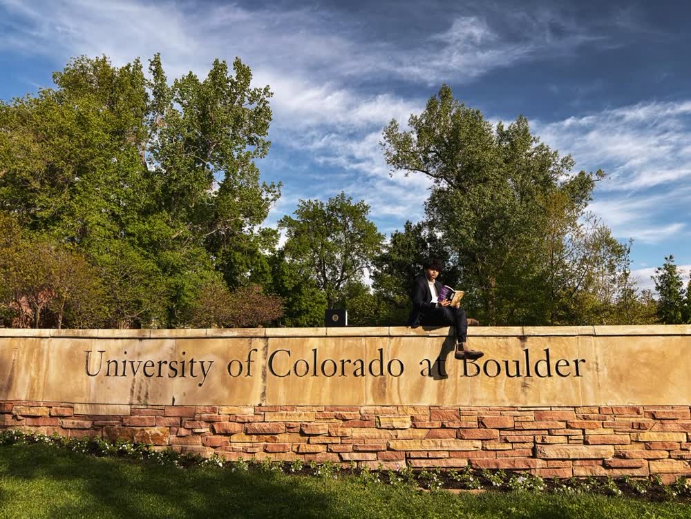 Shubhankar reading on top of the University of Colorado at Boulder sign