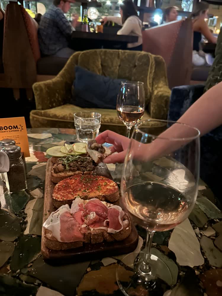 A bruschetta board and glasses of Moscato on a table at Postino’s
